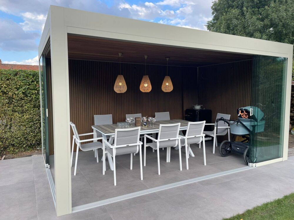 Aluminium terrasoverkapping met glazen schuifwanden en houten wand, ingericht als overdekte eethoek in de tuin